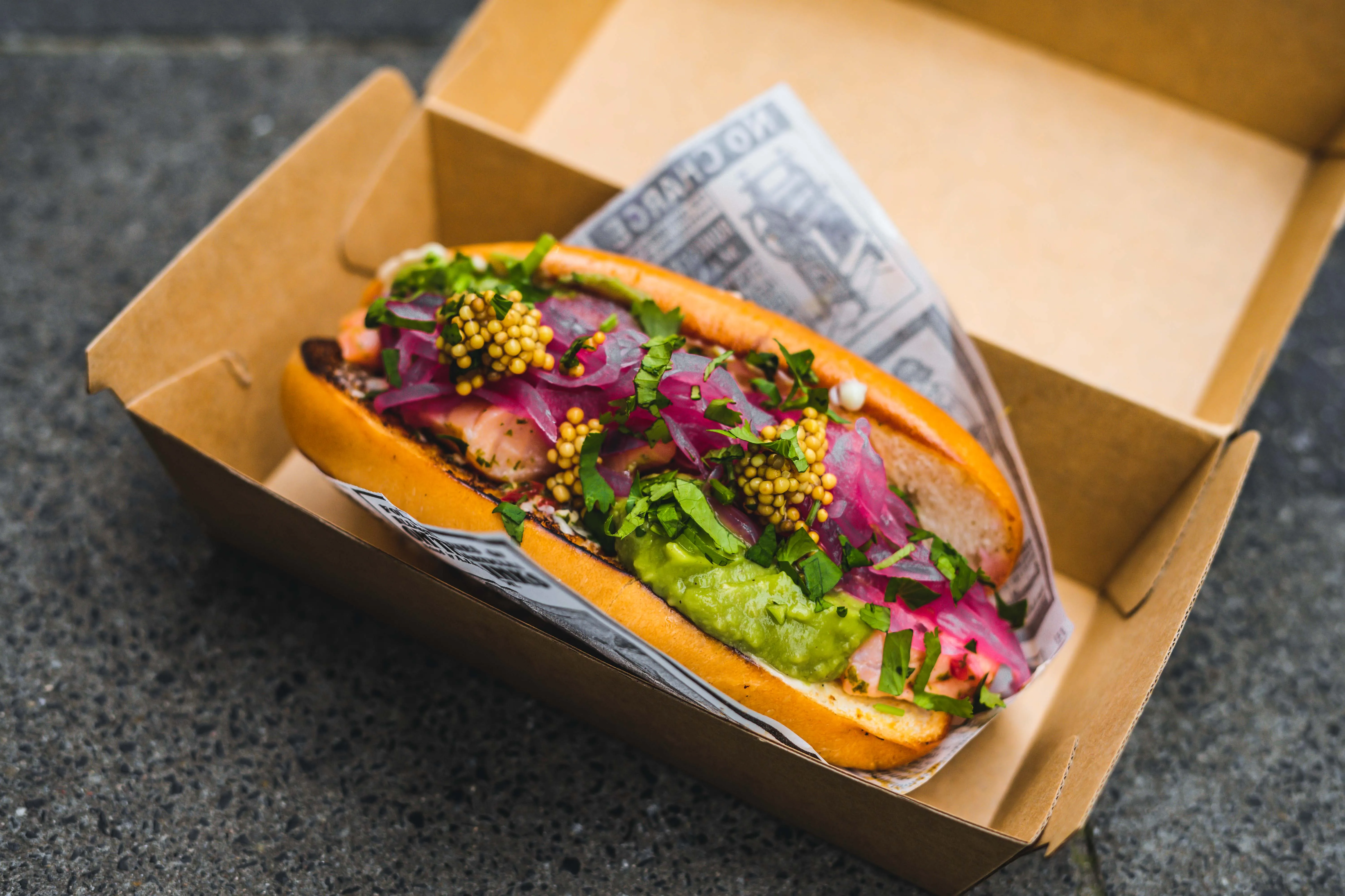 Vegetable-forward street food hot dog in a takeaway box