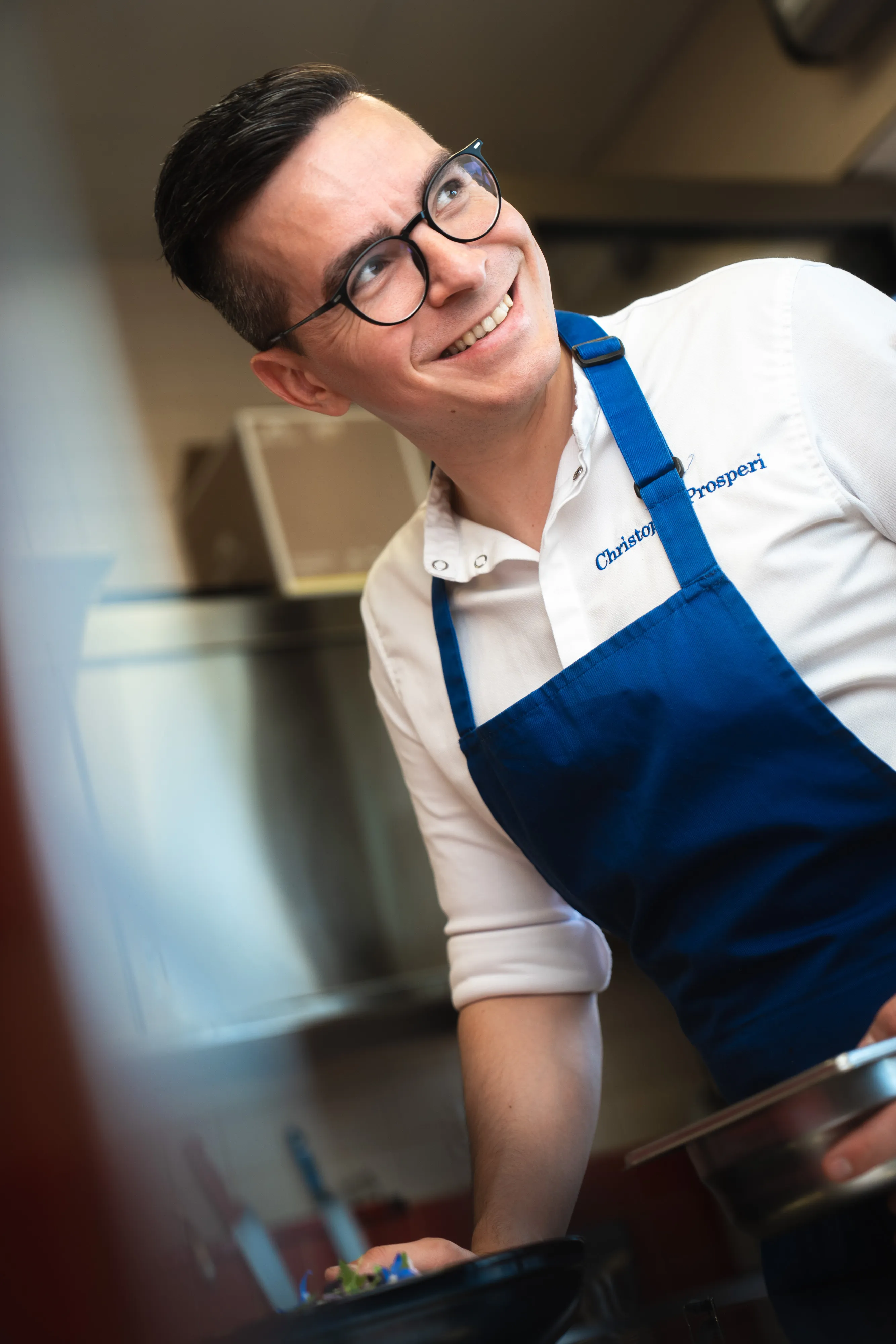 Christophe Prosperi in his kitchen, wearing a blue apron