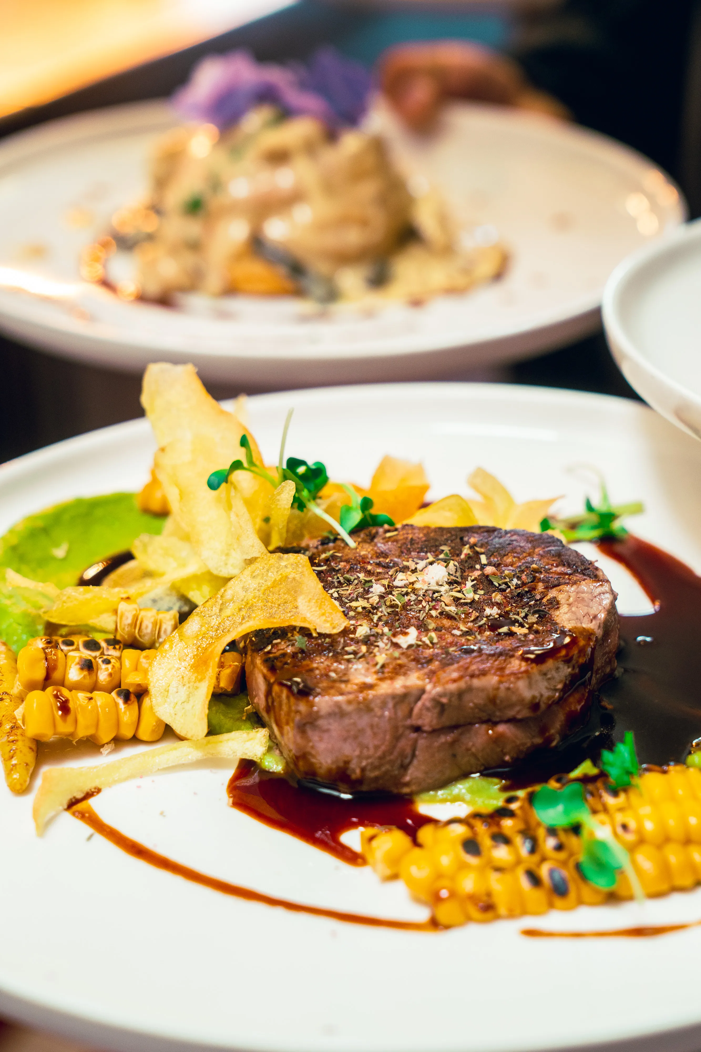 Steak with pea purée, crisps and grilled corn