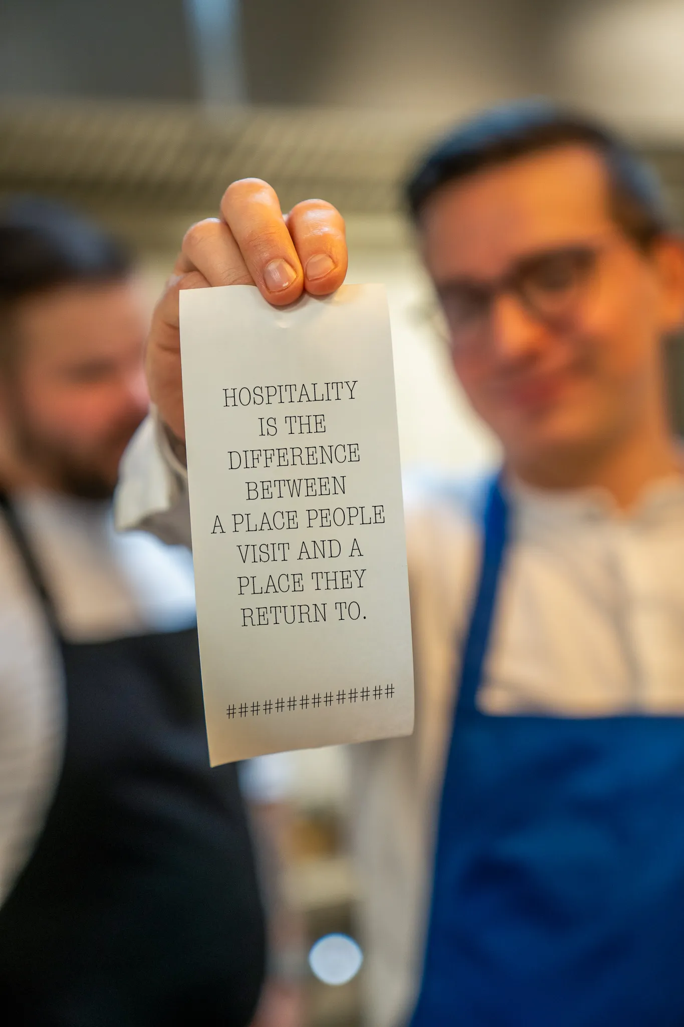 The Restaurant Living team holding a card that reads: hospitality is the difference between a place people visit and a place they return to
