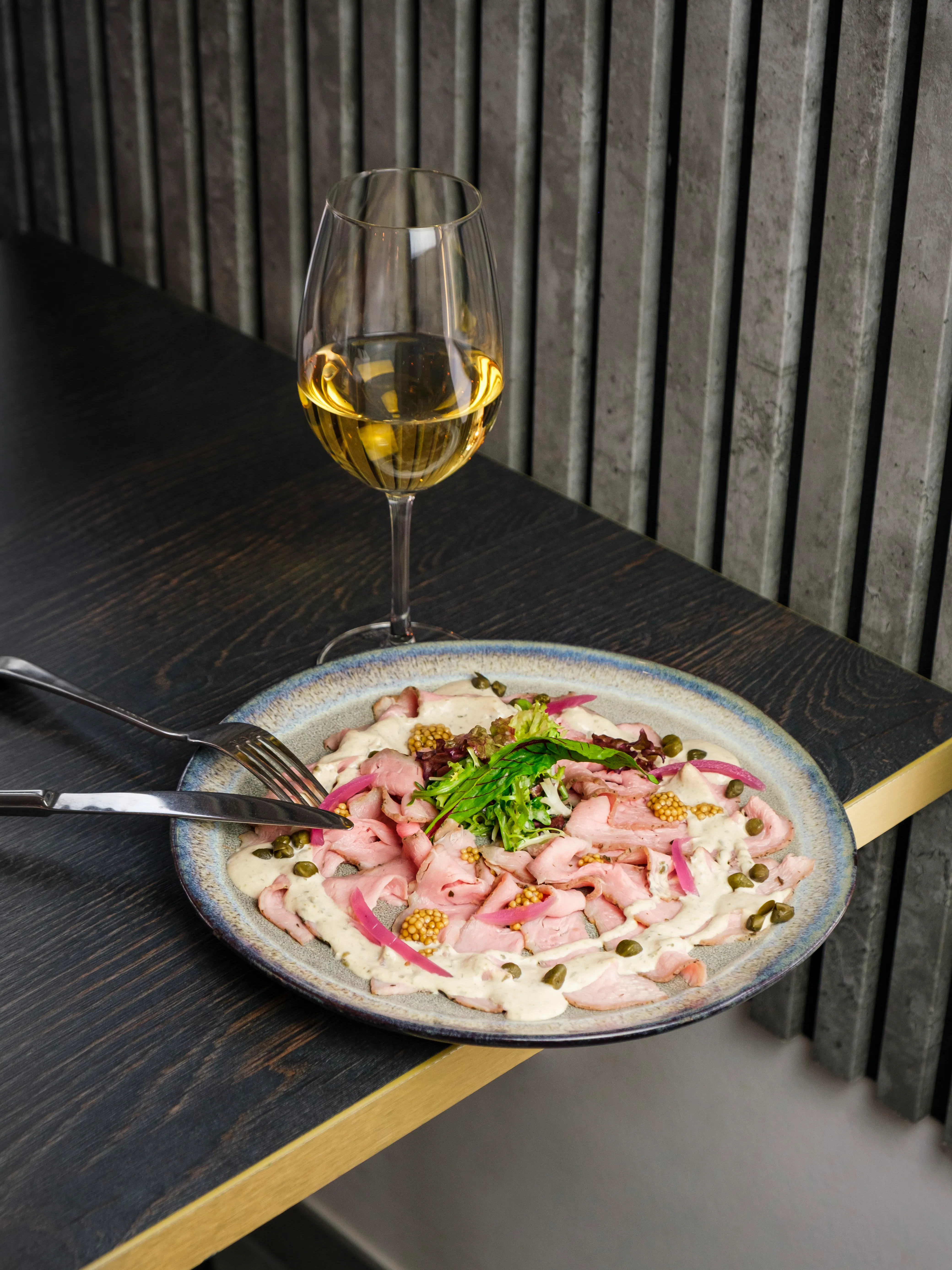 Sliced roast with creamy dressing and a glass of white wine